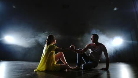 Zoom-camera.-Modern-romantic-choreography.-Love-is-on-stage.-A-man-and-a-woman-dance-together-a-funny-dance-in-jeans-and-a-yellow-dress-on-stage-in-smoke.-Musical.